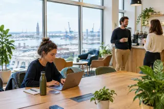 Modern coworking space in Le Havre with large windows, natural light, three people chatting or working, and a relaxed, professional atmosphere.