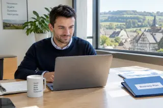 Young entrepreneur at a desk with a laptop and business documents in a modern, sunlit office, Normandy landscape visible outside the window.